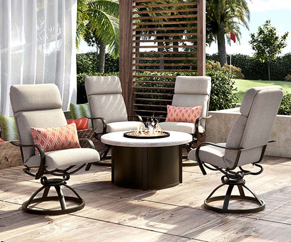 A photo depicts a setting of patio furniture surrounding a circular fire table. The chairs are high-backed and cushioned in grey fabric with orange accent pillows.