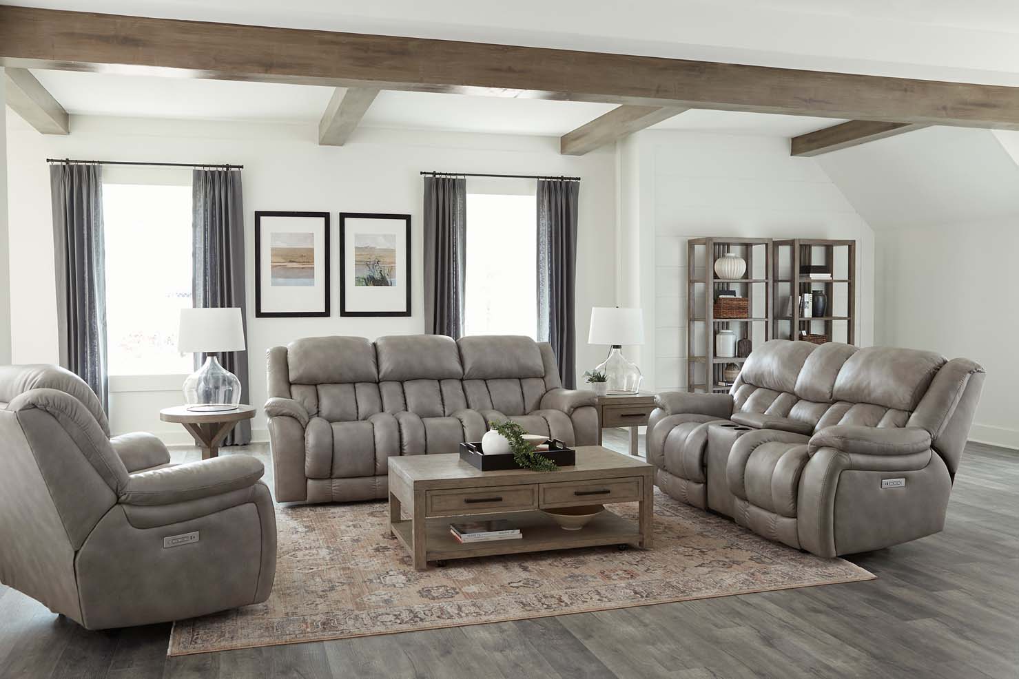 set of mottled grey leather couch, loveseat, and chair sit inside of a modern living room with white walls and wooden beams.