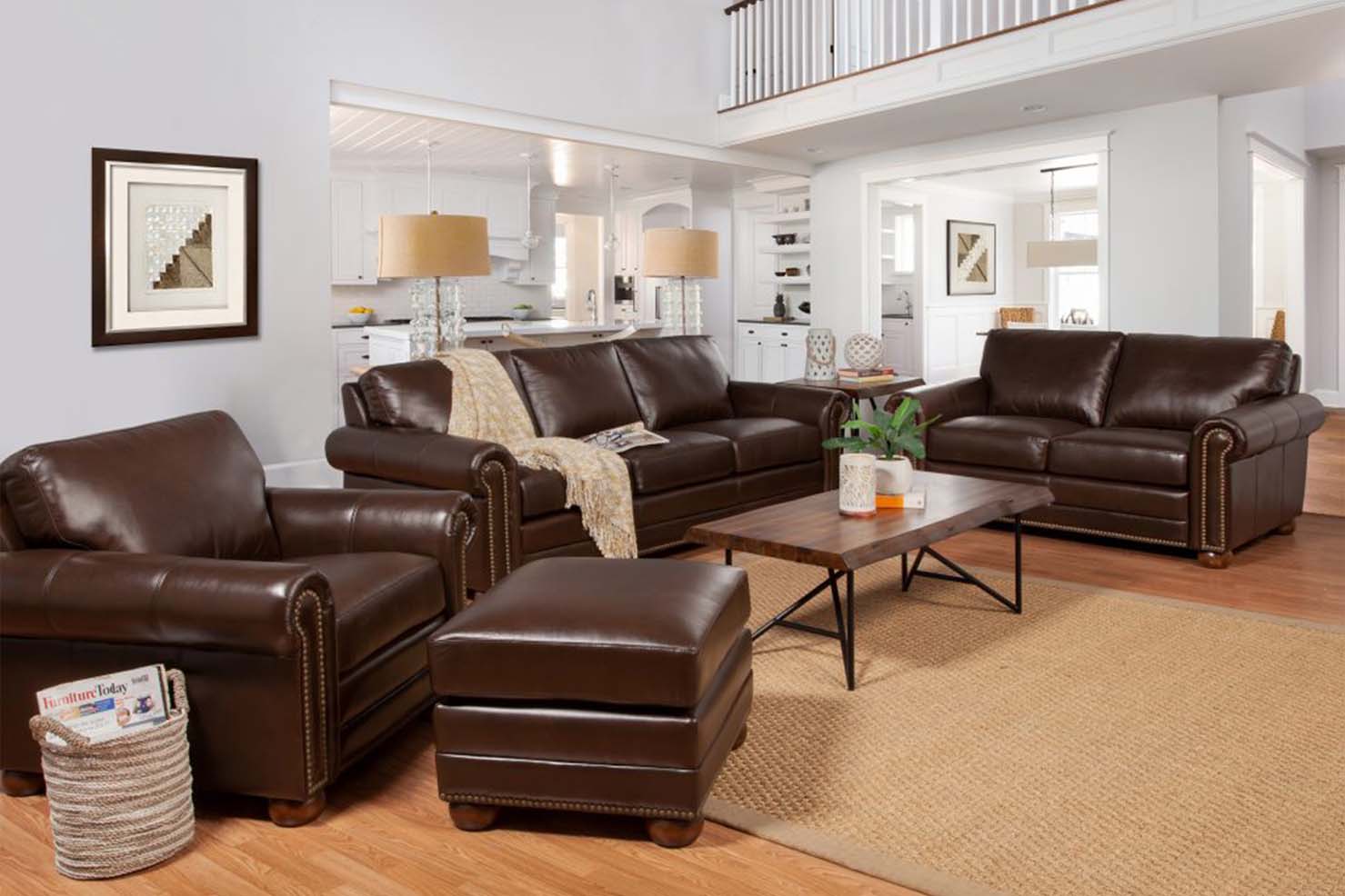 A set of sleek, dark brown leather chair, sofa, and loveseat sit together in a spacious living room.