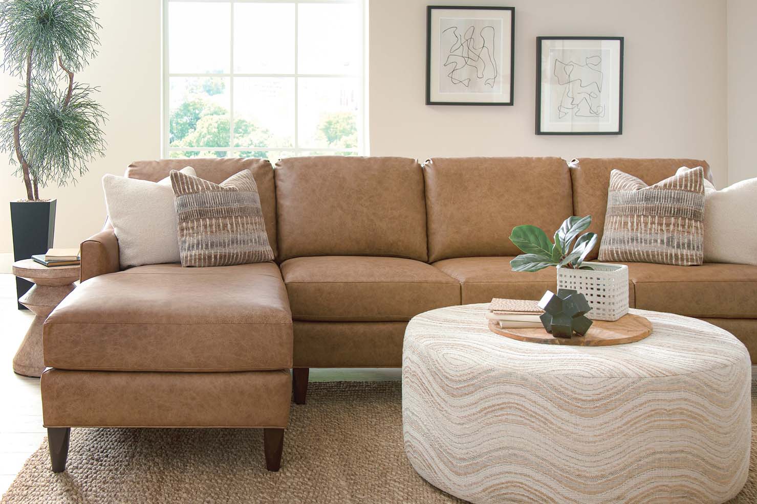 A short sectional with a patterned ottoman is upholstered in a camel-colored leather.