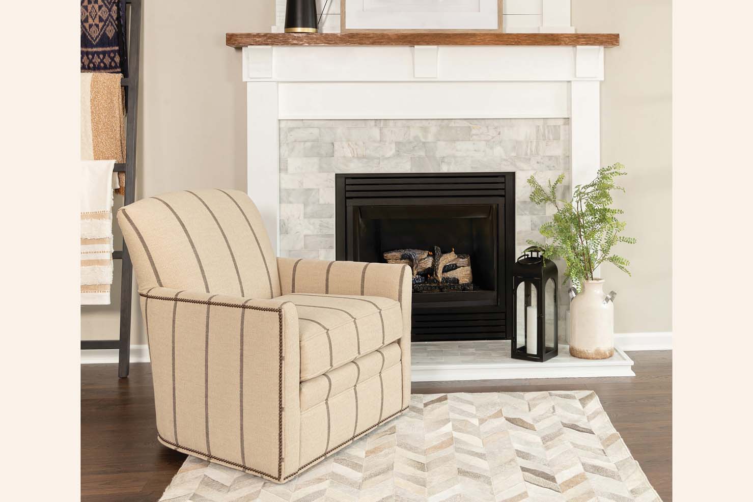 An occasional chair upholstered in a cream pin stripe pattern sits in front of a white brick fireplace.