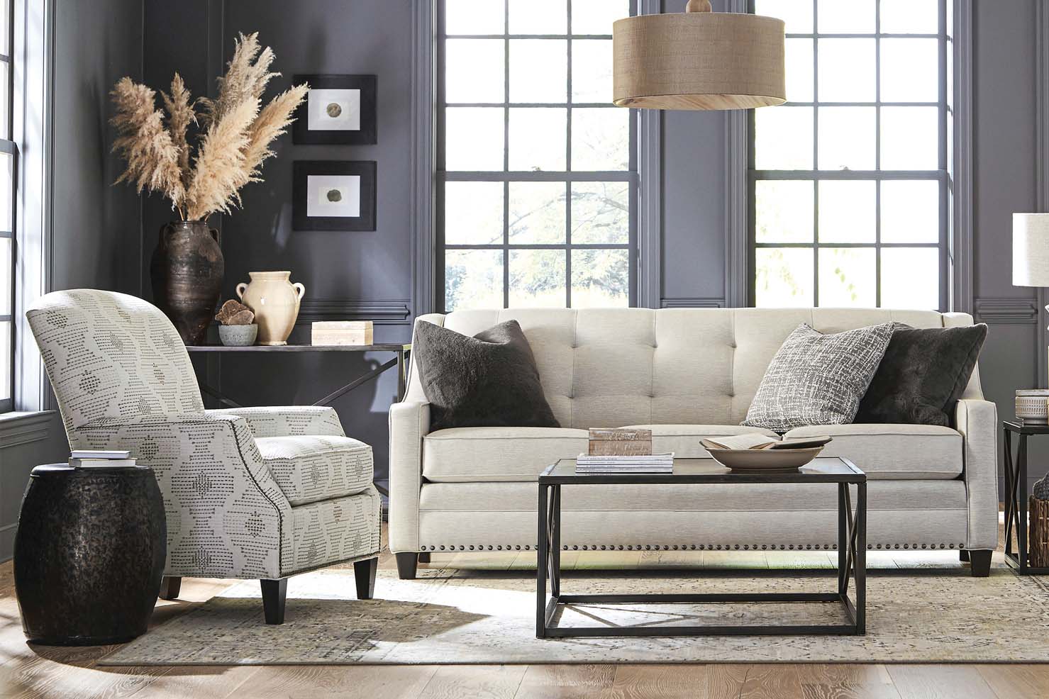 A tufted white fabric sofa and a patterned side chair sit next to each other in a dark grey living room.