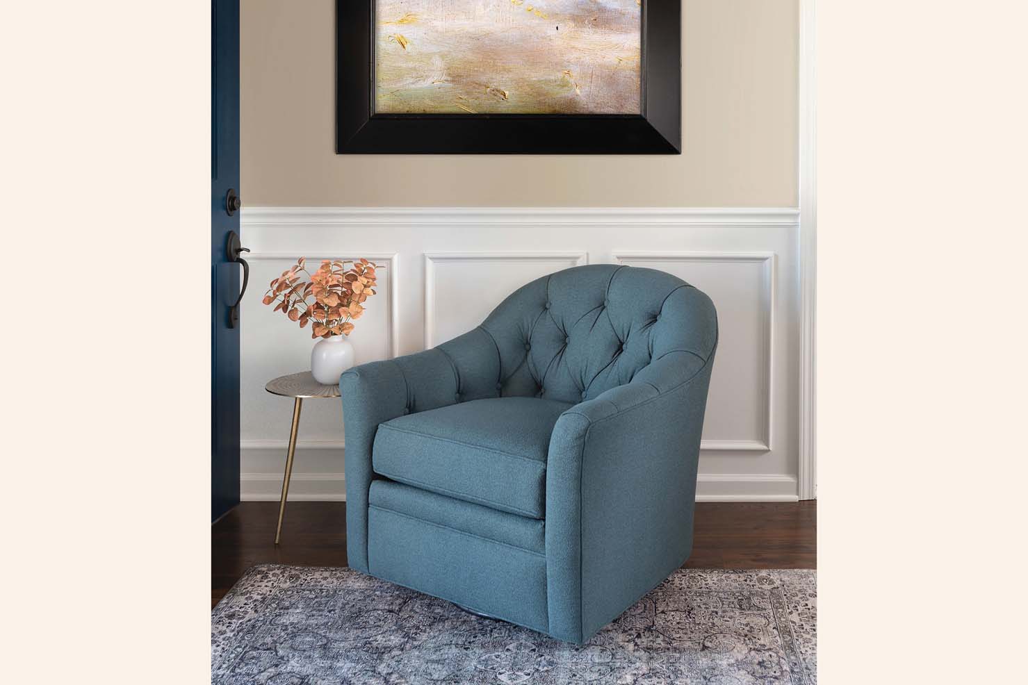 A lower swivel chair is upholstered in a blue fabric and has a tufted interior.