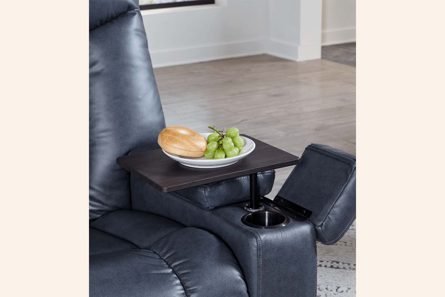 A photo of a blue power recliner displays its adjustable table and drink holder that is constructed in the arm.