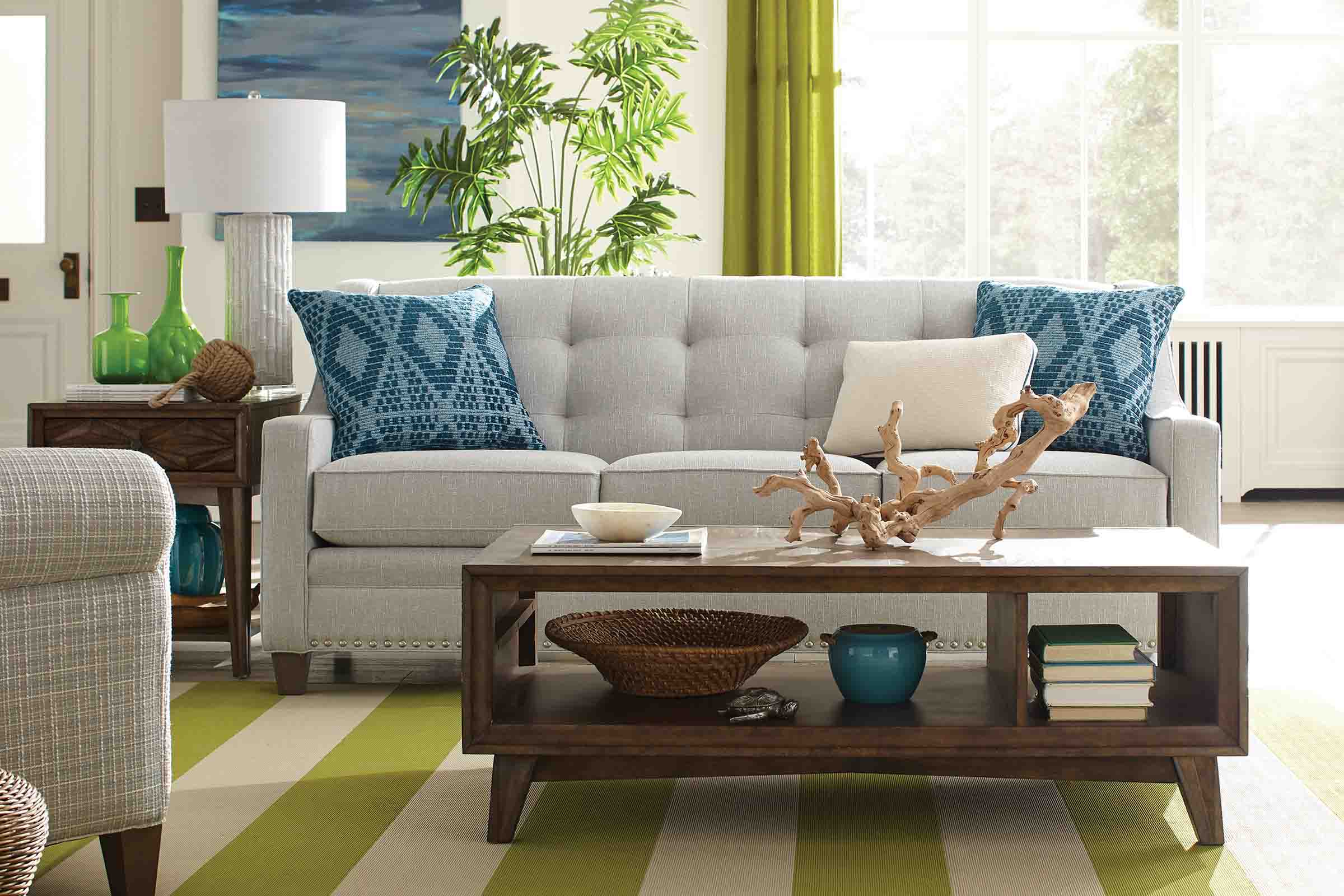 A tufted white fabric sofa and a patterned side chair sit next to each other in a dark grey living room.